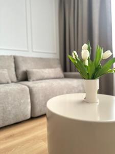 a white coffee table with a vase of flowers on it at Willa Ada Pokoje & Apartamenty in Karwia