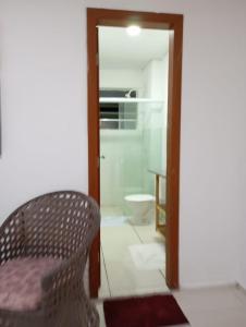a room with a chair and a bathroom with a toilet at Flat 152 e 134 Amarracao shopping luis correia-PIAUI in Luis Correia