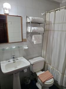 a bathroom with a sink and a toilet and a mirror at Hotel Escorial in La Serena
