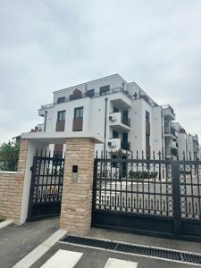 una casa blanca con una valla negra y un edificio en Apartman Vuk, en Vrnjačka Banja