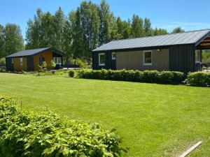 a small building with a grassy yard in front of it at Carpinus II domek nad jeziorem in Łętowo