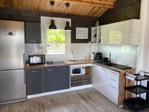 a kitchen with white cabinets and a stainless steel refrigerator at Carpinus II domek nad jeziorem in Łętowo