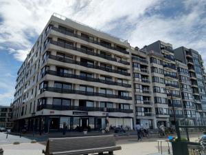 ein großes Gebäude mit einer Bank davor in der Unterkunft SeaStay in Knokke-Heist