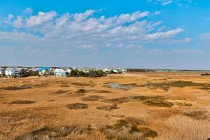 カロライナビーチにあるMarsh Mellow by Carolina Beach Realtyの家屋を背景にした草原
