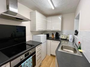 a kitchen with white cabinets and a sink and a stove at Newquay Fistral Beach View with pool in Newquay