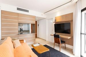 ein Wohnzimmer mit einer Couch und einem Tisch und einem Fernseher in der Unterkunft ARK Houses - Flat Vista-Mar - Piscina na Cobertura in Santos