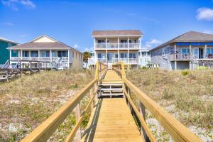 a wooden boardwalk leading to houses on the beach at Next Time Down by Carolina Beach Realty in Kure Beach