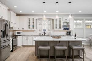 a kitchen with white cabinets and a large island with bar stools at The Nedonna Nest in Rockaway Beach