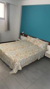 a large bed in a bedroom with a blue wall at Apartamento T1 - Hotel Las Rochas in Mindelo