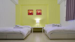a room with two beds and a table with a lamp at STSP Guest House in Xinshi