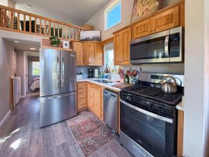 a kitchen with stainless steel appliances and wooden cabinets at Apple Blossom Bungalow in Sequim