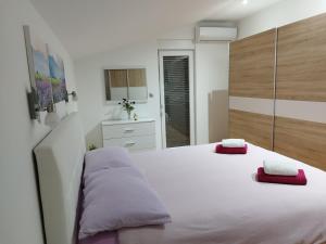 a bedroom with a large white bed with red pillows on it at Tolj apartman in Ljubuški