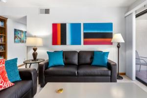 a living room with a black couch and blue pillows at Downtown Winner at Plaza Villas by ACME House Company in Palm Springs +28 photos