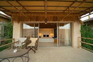 a patio with a bedroom and a bed and a table at Le Bédouin agafay in Marrakesh