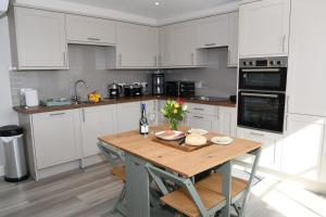 a kitchen with white cabinets and a wooden table at Birch Cottage in Laggan