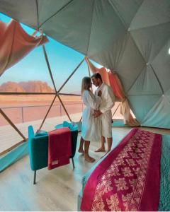 Un uomo e una donna che si baciano davanti a una tenda di RUM CAMILLA lUXURY CAMP a Wadi Rum