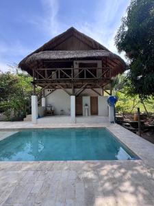 a villa with a swimming pool and a hut at City Escape Casa Mariguana in Turbaco