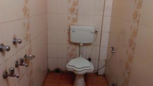 a bathroom with a toilet and a tiled wall at Hotel Prince B in Guwahati