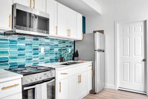 a kitchen with white cabinets and blue tile on the wall at Urban Nest #2 Vibrant suite downtown by Proctors in Schenectady