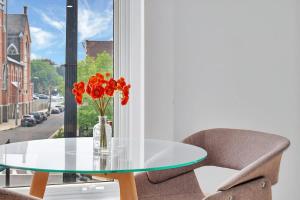 a glass table with a vase of flowers and a chair at Urban Nest #3 Bright loft steps to Proctors in Schenectady +8 photos