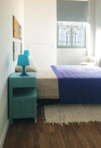 a bedroom with a bed with a blue lamp on a night stand at O Sardinhas in Matosinhos