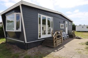 a black tiny house with a porch and windows at Nette chalet nabij het bos in Anloo