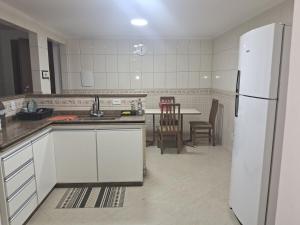 a kitchen with white cabinets and a white refrigerator at Salt Lake Suítes in Arraial do Cabo