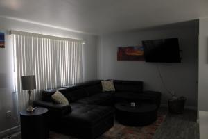 a living room with a black couch and a flat screen tv at Purple Mountain Majestic Retreat in Colorado Springs