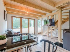 un soggiorno con TV, tavolo e sedie di Zagroda ciszy a Lubiatowo