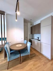 a kitchen with a table and blue chairs in a room at Luxe Beachfront Stay in Bečići with Pool in Budva