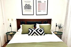 a bedroom with a bed with pillows and pictures on the wall at Santiago Urbano Apartments - Centric Santiago in Santiago