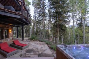 a hot tub on a patio with red chairs at Alpenglow by Exceptional Stays in Telluride