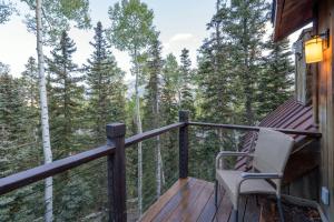 a deck with a chair and a view of the forest at Alpenglow by Exceptional Stays in Telluride