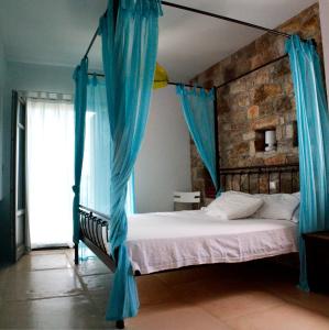 1 dormitorio con cama con dosel y cortinas azules en Villa Penelope - Marathopoli, en Marathopolis