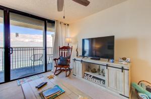 a living room with a television and a balcony at Pelican Watch in Carolina Beach