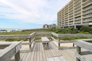 a wooden bench on a boardwalk near the beach at Pelican Watch 706: Sea You Next Time by Carolina Beach Realty in Carolina Beach