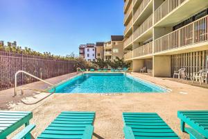 a swimming pool with blue chairs and a building at Pelican Watch 706: Sea You Next Time by Carolina Beach Realty in Carolina Beach