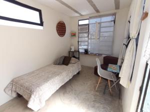 a bedroom with a bed and a desk and a window at Casa Ha Hostal in Mérida