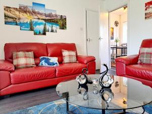 a living room with a red couch and a glass table at Cozy 2BR Home Leeds Free Parking & Wifi Pets Welcome in Belle Isle