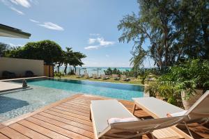 a swimming pool with two lounge chairs and the ocean at Moorea Beach Villas in Haapiti