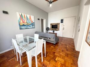 une salle à manger avec une table en verre et des chaises blanches dans l'établissement Apê Vista Mar - 50m da Praia Pitangueiras, à Guarujá