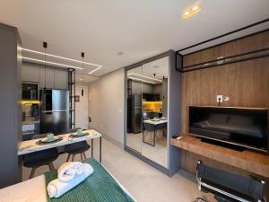 ein Wohnzimmer mit Küche und großem Fernseher in der Unterkunft Studios com piscina na cobertura - City House in Barreiras