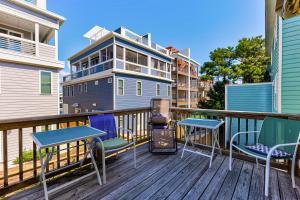 un balcón con sillas y mesas y un edificio en Poopka & Dennys Beach Condo by Carolina Beach Realty, en Carolina Beach