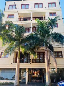 a building with palm trees in front of it at THE HEIRS Departamentos in Posadas