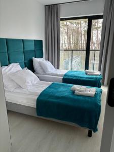 - une chambre avec 2 lits avec des couvertures bleues et une fenêtre dans l'établissement Apartament Słoneczny AKTENA Shellter Rogowo, à Rogowo