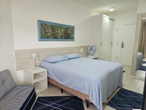 a bedroom with a bed and a chair in it at Loft Reserva do Sahy in Mangaratiba