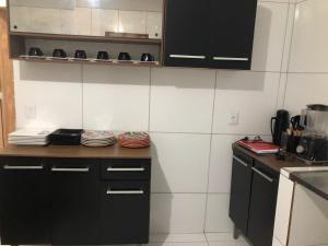 a kitchen with black cabinets and plates on a counter at Pousada dos Artistas in Japaratinga