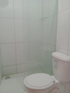 a bathroom with a toilet and a white tiled wall at Pousada dos Artistas in Japaratinga