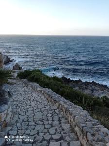 a stone path next to the ocean with the horizon at Case Nereidi 2 in Porticello
