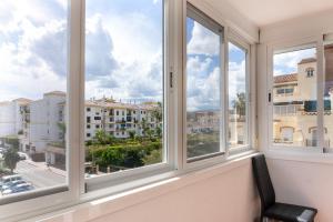 a room with three windows looking out at the city at Apartamento ROMA in Torre del Mar